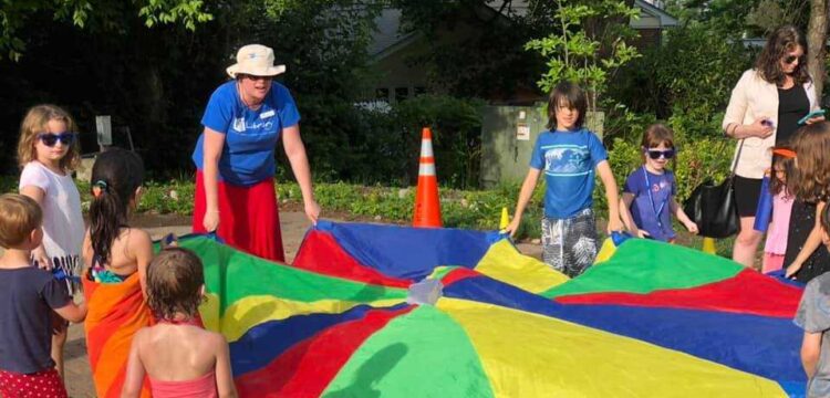 Children and adults play with a parachute.