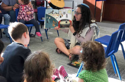 A rabbi reads a book to children.