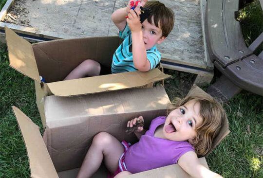 Two children play in boxes.